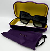 A pair of Gucci square frame sunglasses with shiny black injection frame, black glitter temples