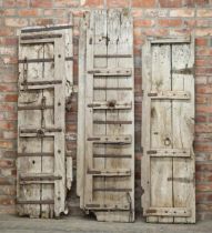 Three rustic possibly Haveli door panels, bleached oak with iron strapwork, the largest 195 x 52cm