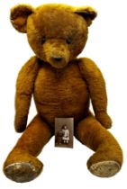 Large vintage straw stuffed bear with articulated limbs and leather pads, 90cm high, with original