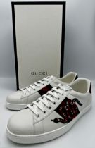 A pair of Gucci snake embroidered Ace low-top white leather trainers. Featuring padded tongue and