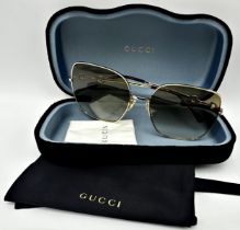 A pair of Gucci gold full-rim square metal sunglasses with brown gradient lenses featuring iconic