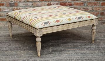 Large contemporary kilim upholstered footstool with studded edging, carved detail, raised on