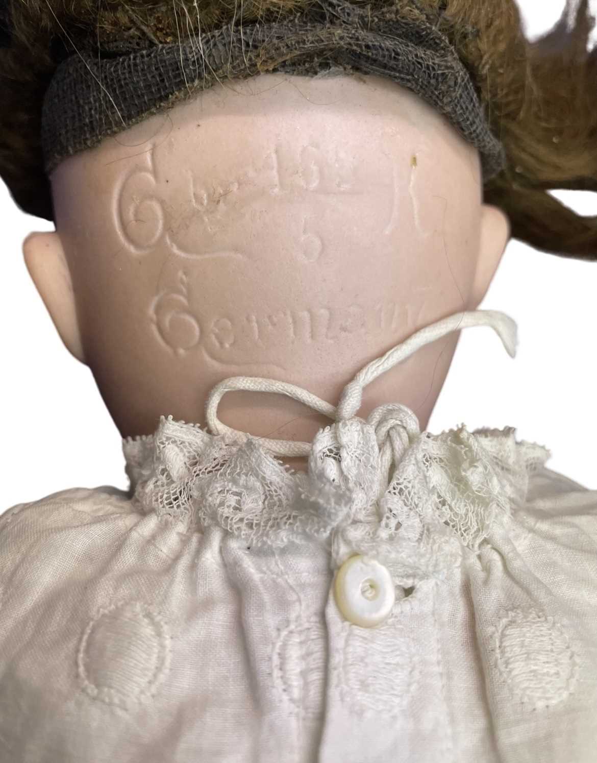 G&K bisque head doll in white dress. Blue eyes and brown hair. Marked to back of head 165 5. - Image 2 of 2
