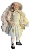 French bisque head doll in cream dress and cape with bonnet and black shoes. Blue eyes, lacking