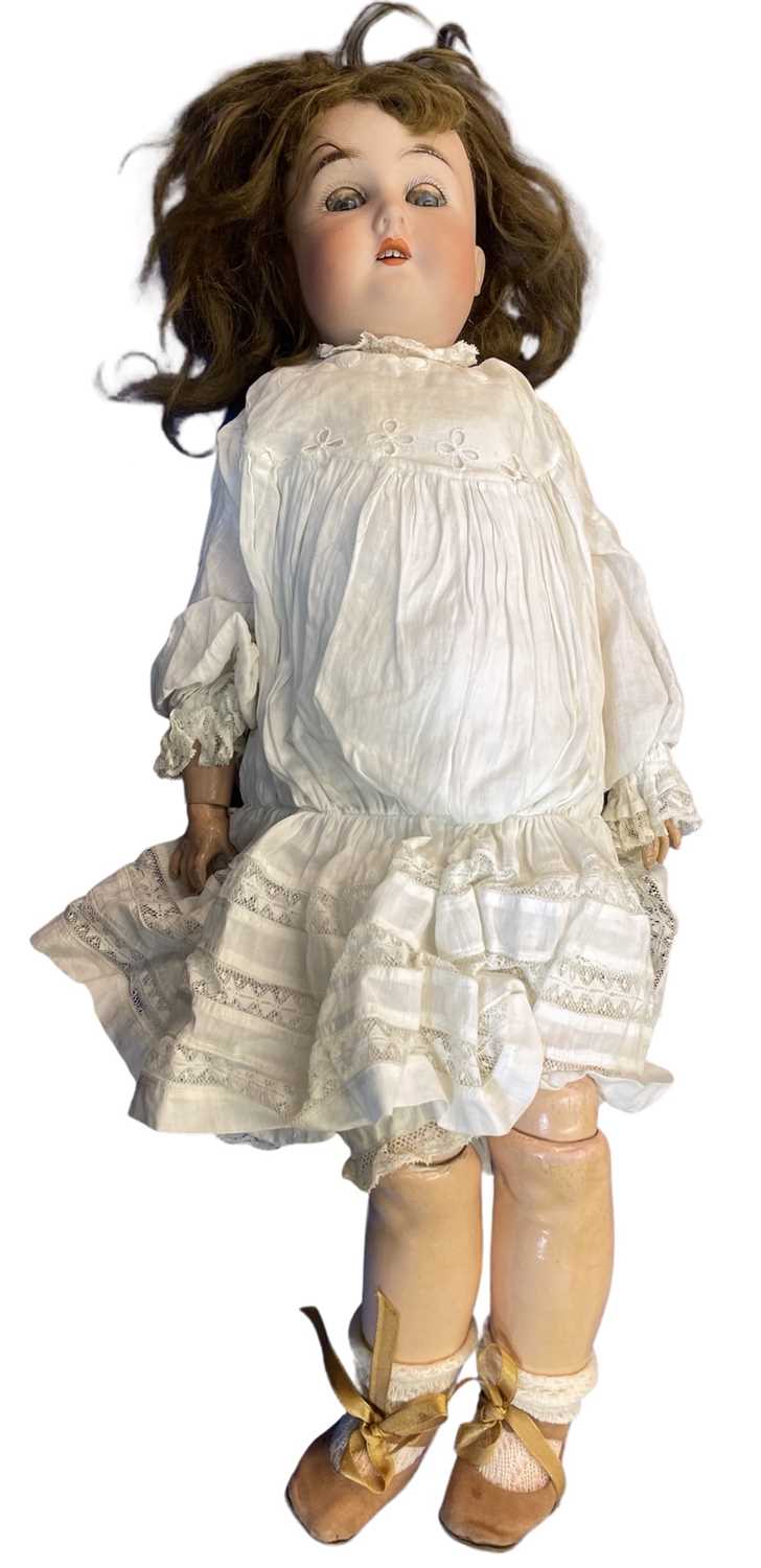 G&K bisque head doll in white dress. Blue eyes and brown hair. Marked to back of head 165 5.