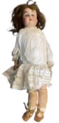 G&K bisque head doll in white dress. Blue eyes and brown hair. Marked to back of head 165 5.