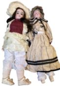 Pair of large bisque head dolls, formed as ladies in dresses and bonnets. Length approximately