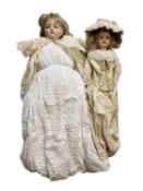 A pair of interesting wax head dolls in cream and white dresses. Length approximately 60cm.