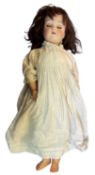 German bisque head doll in white and blue striped dress. Blue eyes and brown hair. Marked to back of