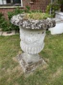 A pair of composite garden urns with square bases