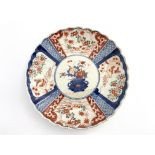 Two Japanese imari plates, one rounded and scalloped form with central floral composition in a vase,