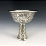 A Chinese white metal libation cup, flared circular bowl chased with exotic birds in flight