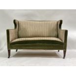 A late Victorian wing back salon settee, circa 1890, upholstered in green velvet and striped fabric,