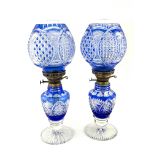 A pair of blue flashed glass oil lamps and shades, with hobnail and star cut decoration, with