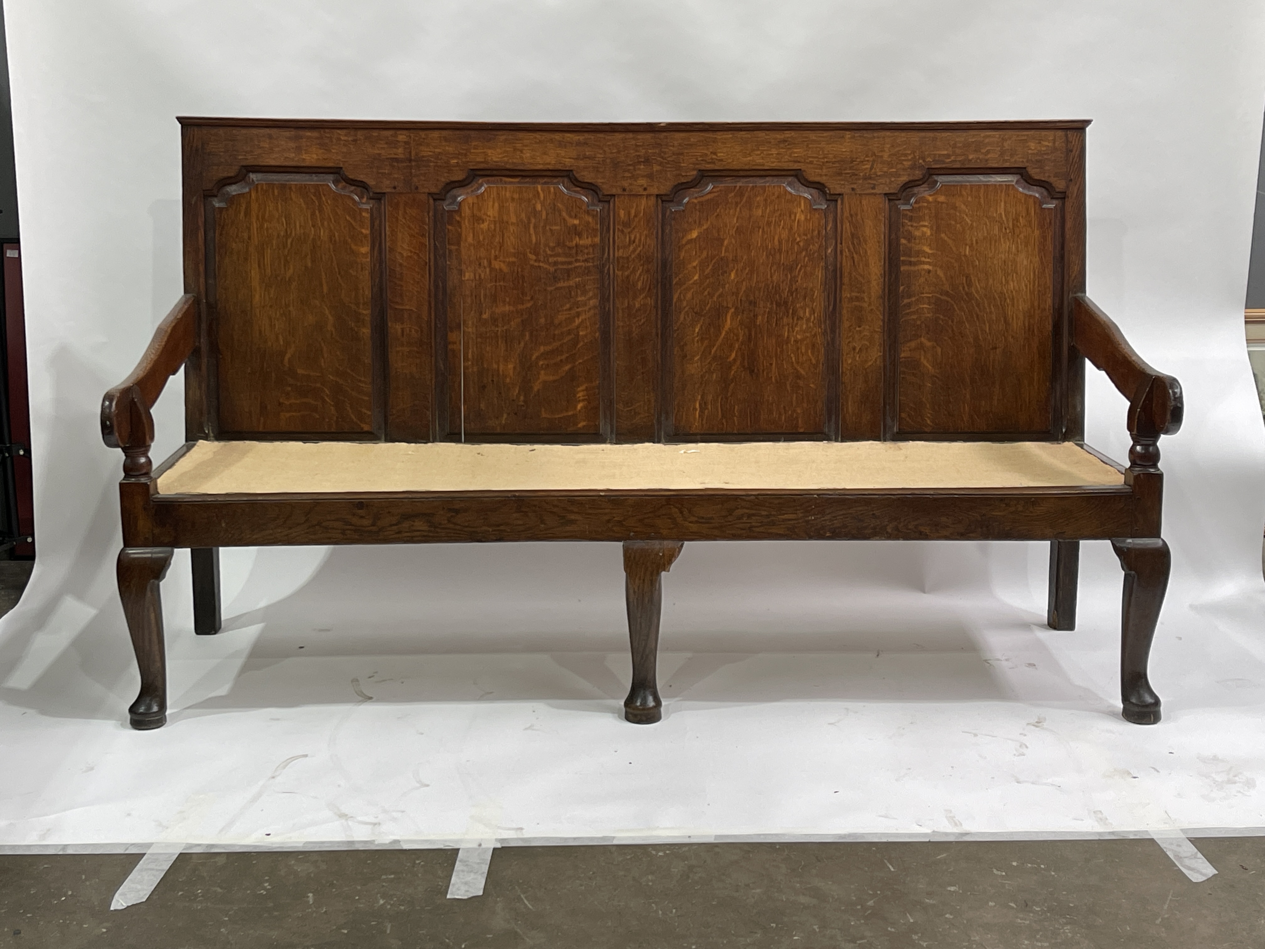 A George III country oak hall settle, circa 1770, four fielded panel back, downswept arms,