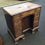 A George II mahogany kneehole desk, the central cupboard flanked by three graduated drawers on