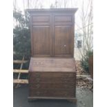 A George III oak bureau bookcase, fall front over four graduated cockbeaded drawers, below two