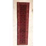 An Afghan style wool runner, polychrome stylised motifs within scroll and motif banded border on red