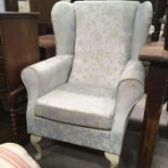 A blue chintz upholstered wing back armchair on painted supports