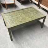 A green painted glass top coffee table, the glazed surface moulded in relief with scrolling leaves
