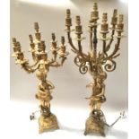 A matched pair of gilt metal figural candelabra modelled as putti holding six branch cornucopia,