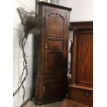 A George III floor standing corner cupboard, three fielded panel door, over single door, 263cm high