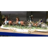 A Capodimonte bisque porcelain model of an open coach and horses, on foliate scroll base, 62cm wide,