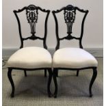 A pair of Victorian ebonised salon chairs, carved foliate lyre splat backs and shell acanthus scroll