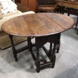 An antique oak gate leg table, pegged oval top above single frieze drawer, on ring turned and
