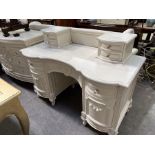 A French style white painted kneehole dressing chest with moulded floral swags on cabriole supports,