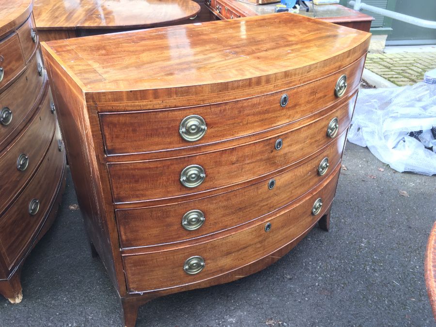 A George III mahogany and satinwood strung bow fronted chest of two short over three long