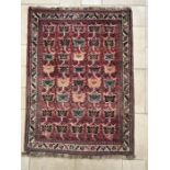 An Afghan style fringed wool rug, foliate motifs within motif cream banded border on a pink ground