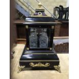 An ebonised and faux tortoiseshell, gilt mounted four decanter display unit, glazed to four sides,