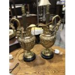 A pair of gilt metal ewer table lamps, in the classical style, modelled in relief with Roman