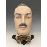 A painted plaster mannequin head model, with fabric collar and bowtie, circa 1940s, 31cm high