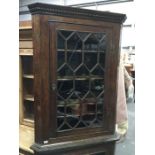 A George III oak hanging corner cupboard, single astragal glazed door, fitted carved ogee shelves