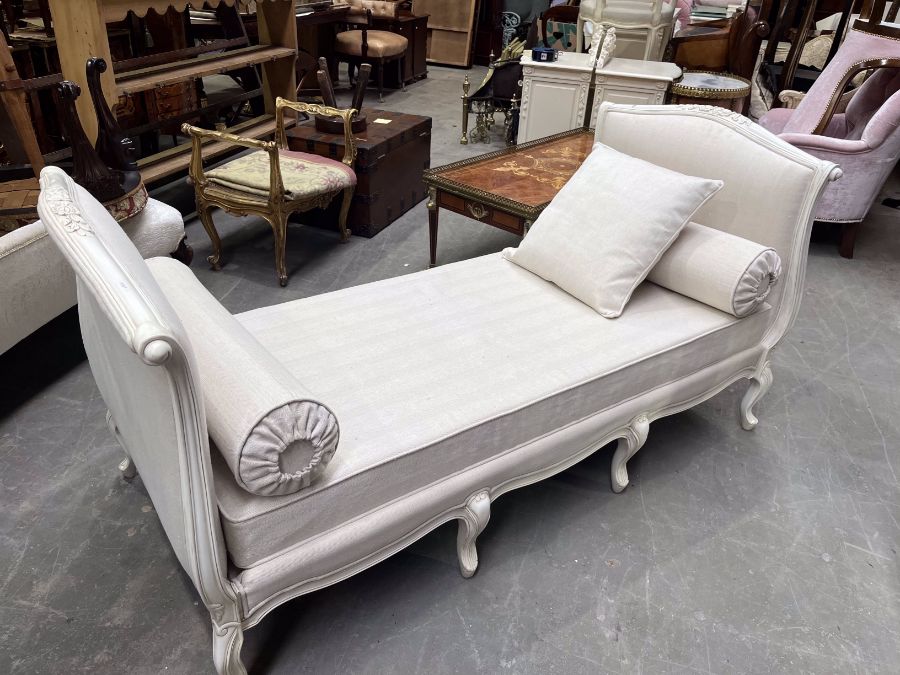 A French style daybed, the white painted frame with moulded floral decoration, on eight cabriole