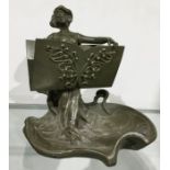 A patinated art metal figural letter holder, in the art Nouveau style, modelled as a woman holing an