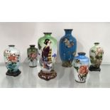 A collection of small Oriental cloisonne enamelled vases and stands, variously decorated, 15.5cm