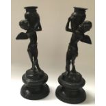 A pair of bronzed metal figural candlesticks, modelled as winged figures, on naturalistic and