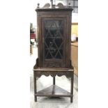 A late 19th century carved oak corner cupboard and stand, with single reeded astragal glazed door,