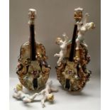 A pair of Italian porcelain moulded cellos with floral encrustations and modelled cherubs, 67cm high