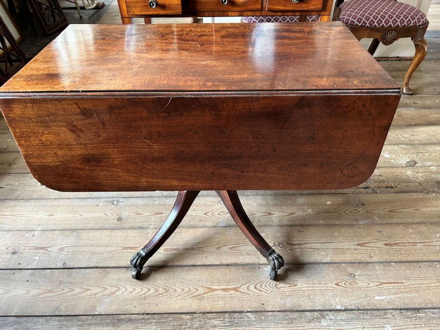 A Regency mahogany Pembroke table, circa 1820, curved end flaps, sabre legs, brass paw cappings