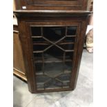 A George III oak hanging corner cupboard, single astragal glazed door, fitted carved ogee shelves,