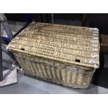 A large wicker linen basket, with hinged lid and strap fastenings 87cm wide