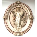 A KPM porcelain wall mounted figural plaque, modelled as a robed classical maiden flanked by cherubs