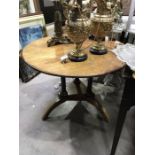 A circular blonde oak occasional table on three pillar supports and chamfered undertier raised on