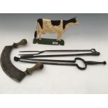 Three wrought iron fire irons, a Mezzaluna with turned wooden handles, and a cast metal model of a