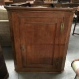 A George III Oak wall hanging corner cupboard, moulded pediment above single panelled door 111cm