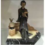 An Art Deco patinated art metal figure, modelled as a woman holding a dove, ascending a stepped
